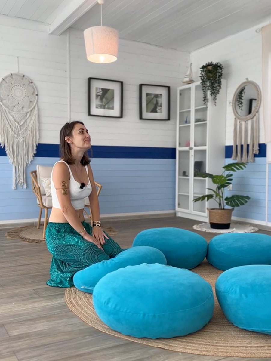 Gospodyni Żeglarskiej Przystani medytuje w sali warsztatowej z niebieskimi poduszkami