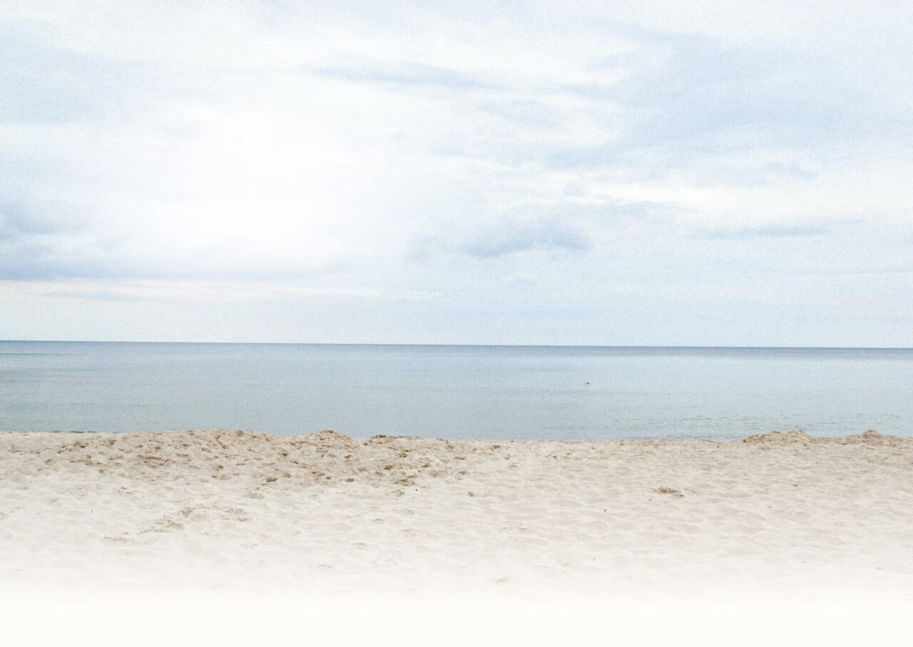 Pusta piaszczysta plaża nad spokojnym morzem w pobliżu Ośrodka Rozwojowego dla Kobiet Żeglarska Przystań